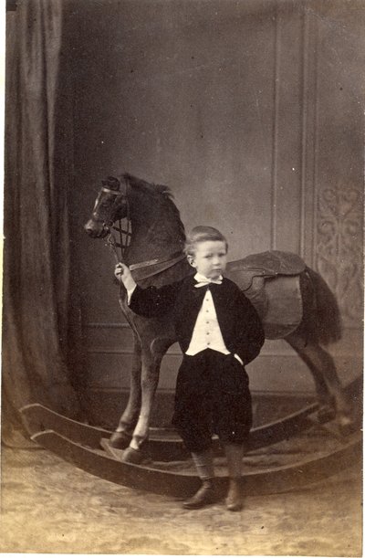 Boy Standing Holding Reins of a Rocking Horse by Barat